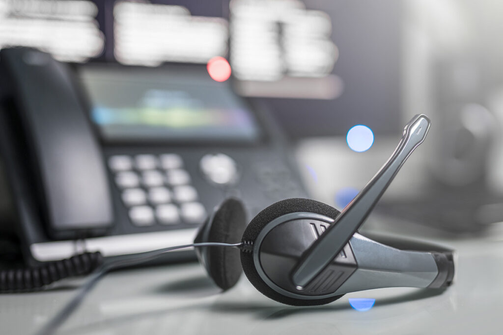 An image of a VoIP headset with a standard business landline behind it, less in focus.