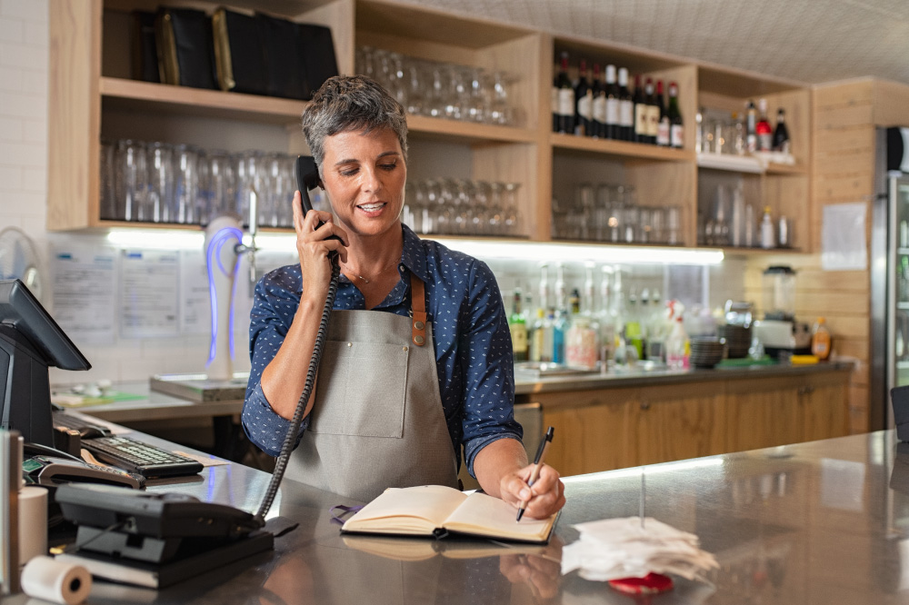 A woman writing in her notebook as she takes a call.